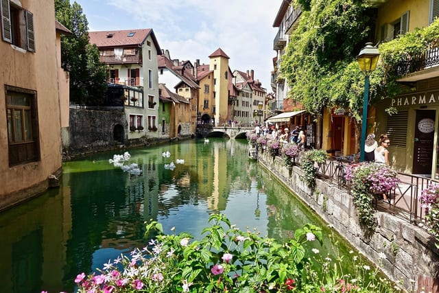 A flower-lined canal between old houses in Annecy.