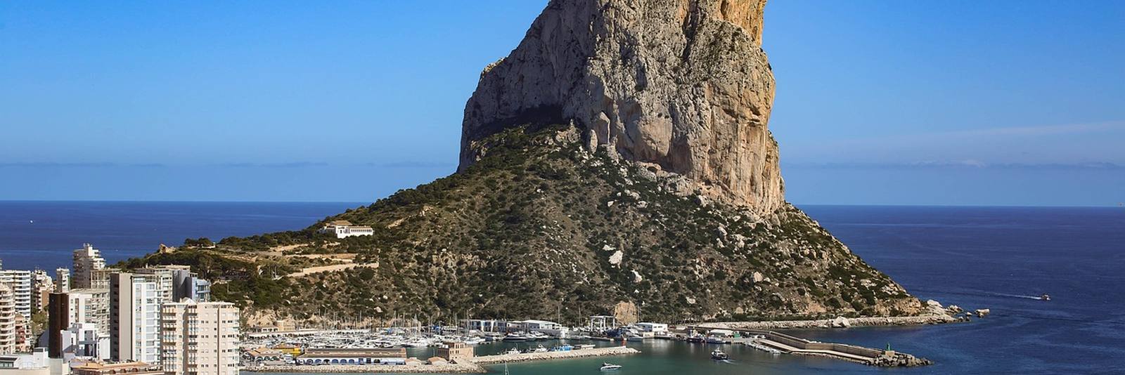 The Peñón de Ifach at Calpe rising straight out of the sea, with the marina and the white blocks of the town at its foot on the left.