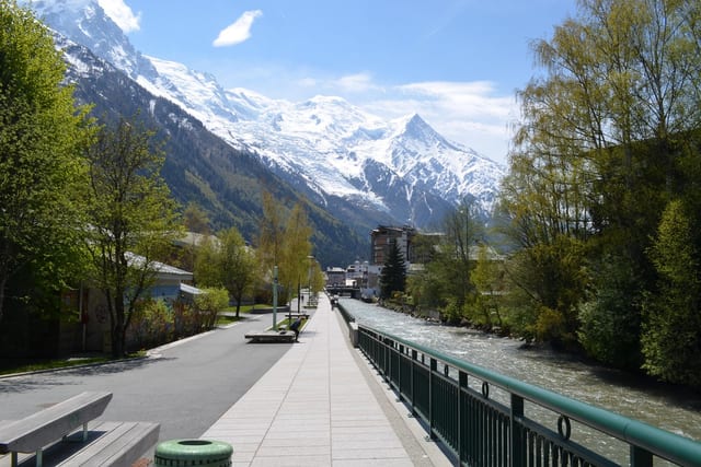A riverside promenade in Chamonix below the snow-covered massif.