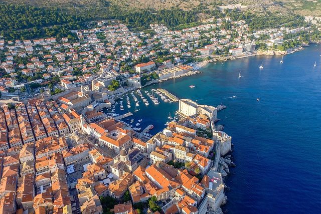 The terracotta roofs of Dubrovnik's old town from the air, running down to boats moored in the old port.