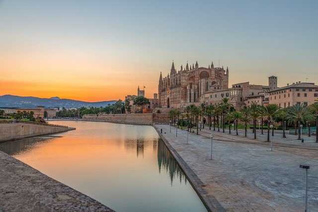 Palma cathedral above the sea wall at sunset, reflected in the water of the Parc de la Mar.