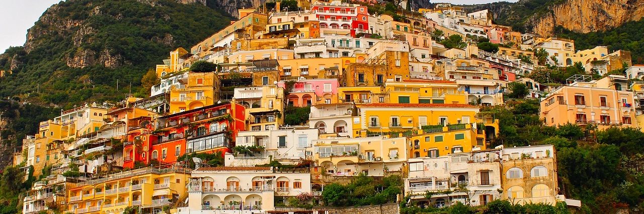 Positano stacked up its hillside above the sea, houses in ochre, pink and cream stepping down the slope one behind another with bare mountain above.