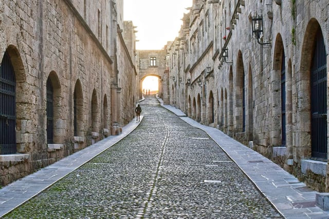 The cobbled Street of the Knights between arched stone buildings in Rhodes old town.