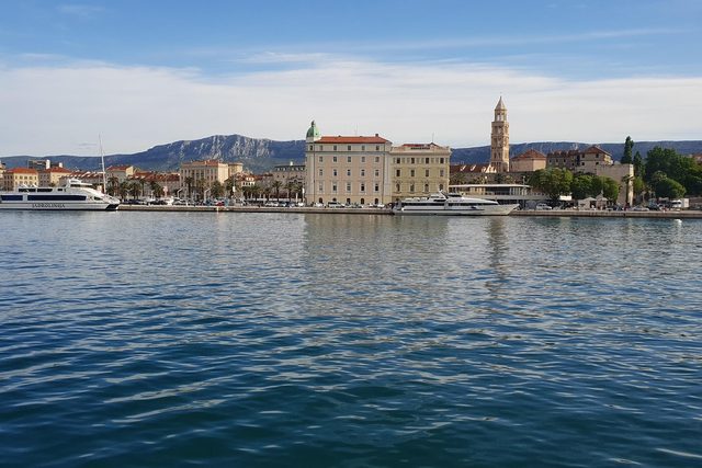 Diocletian's Palace frontage and the cathedral bell tower at Split, seen across the harbour with boats moored along the Riva.