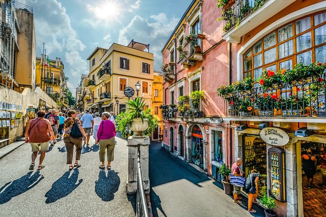 Corso Umberto in Taormina, crowded between shopfronts and flower-hung balconies.